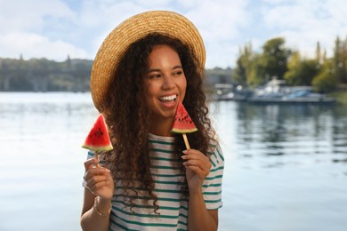 Photo of Beautiful young African American woman with pieces of watermelon near river