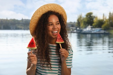 Beautiful young African American woman with pieces of watermelon near river