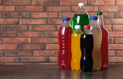 Bottles of soft drinks on table near brick wall. Space for text