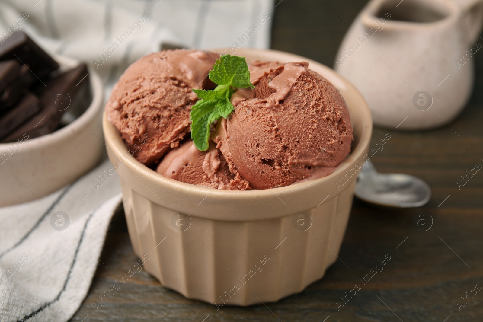 Photo of Bowl of tasty chocolate ice cream on wooden table, closeup