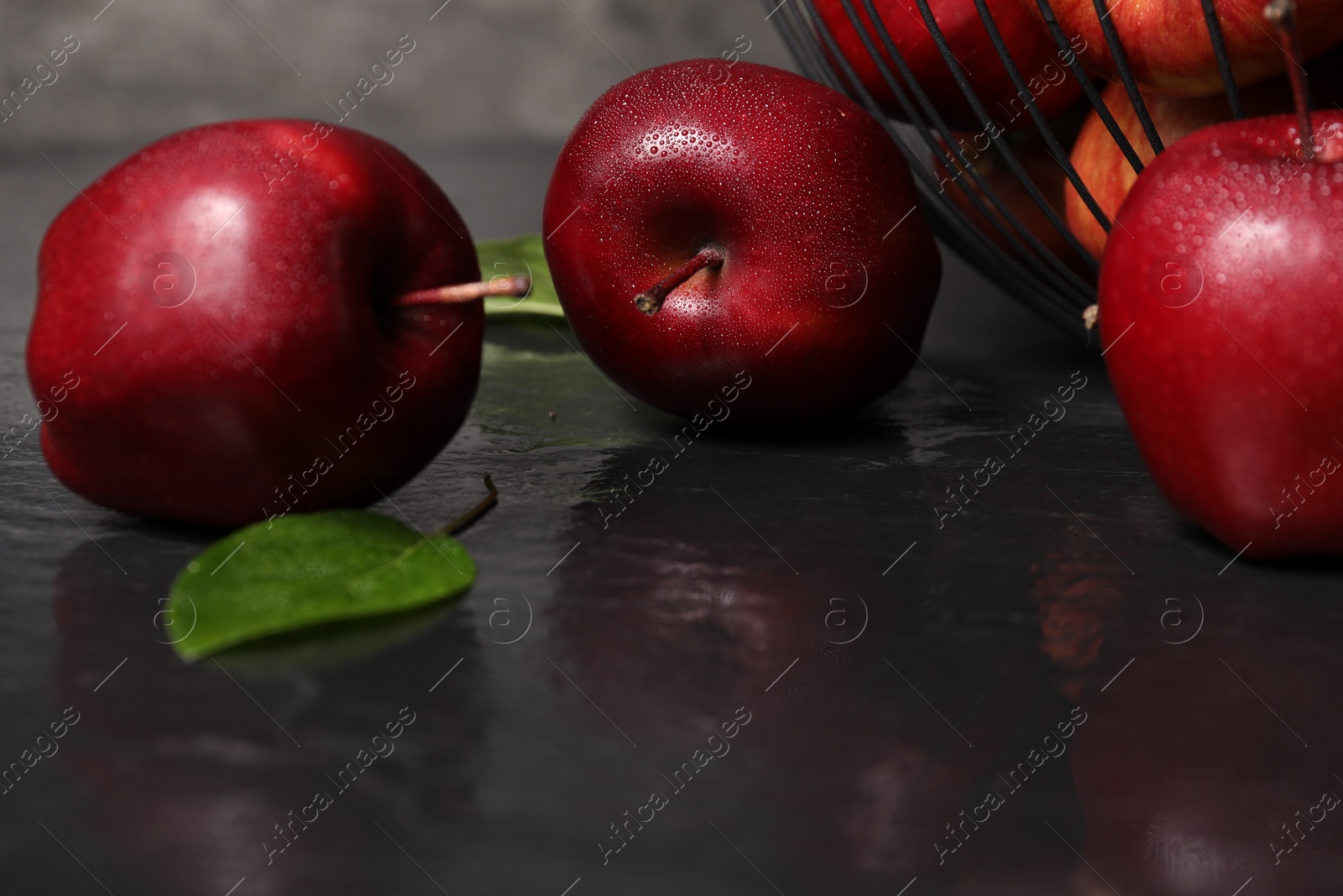 Photo of Ripe red apples with water drops on dark grey table