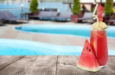 Image of Tasty watermelon drink and fresh fruit on wooden table near outdoor swimming pool, space for text