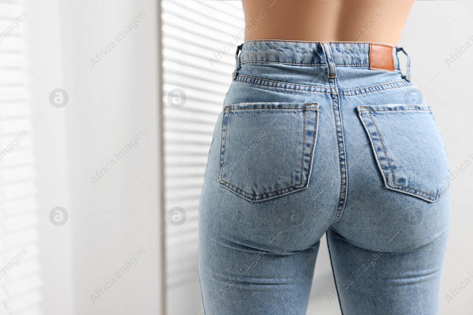 Photo of Woman in stylish jeans indoors, closeup. Space for text