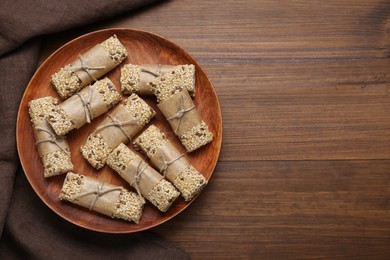 Plate with tasty sesame seed bars on wooden table, top view. Space for text