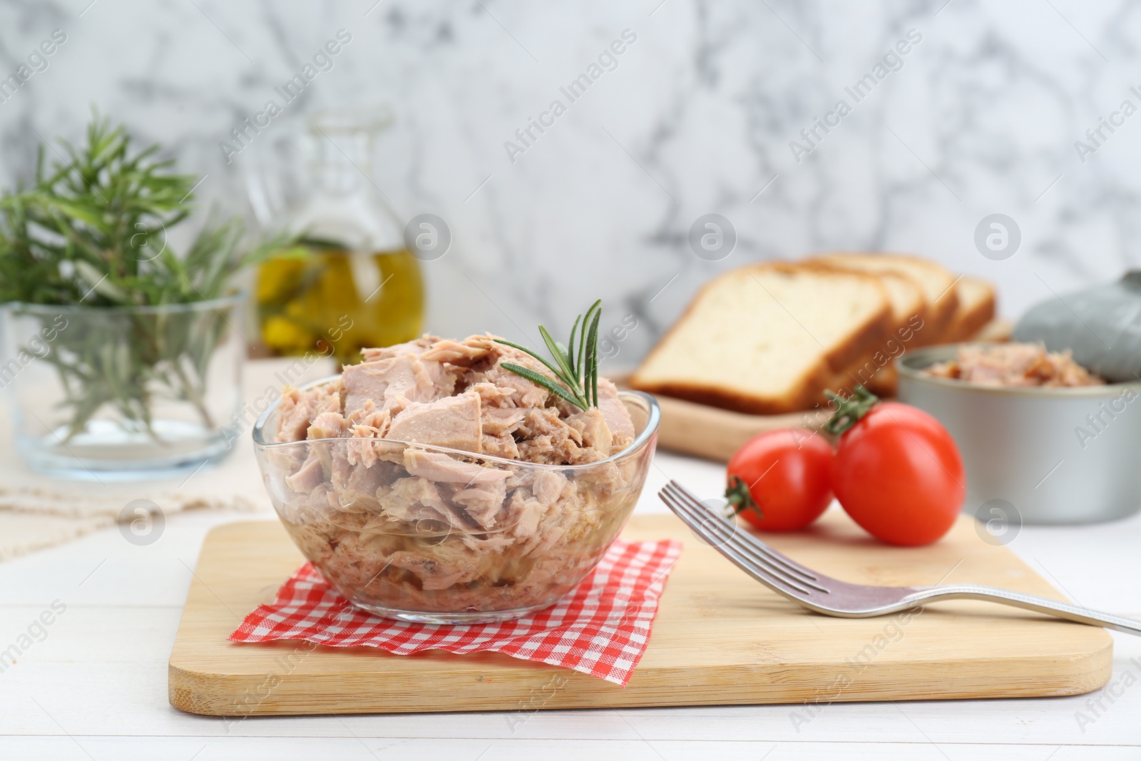 Photo of Bowl with canned tuna and rosemary on white wooden table