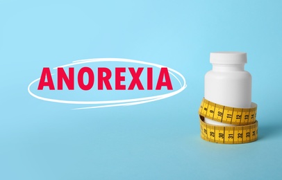 Image of Anorexia concept. Bottle of weight loss pills with measuring tape on light blue background