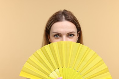 Photo of Woman with yellow hand fan on beige background