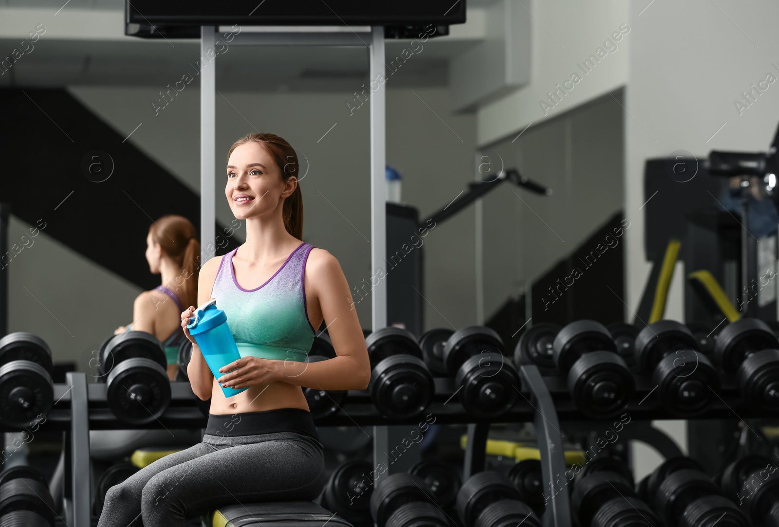 Photo of Athletic young woman with protein shake in gym