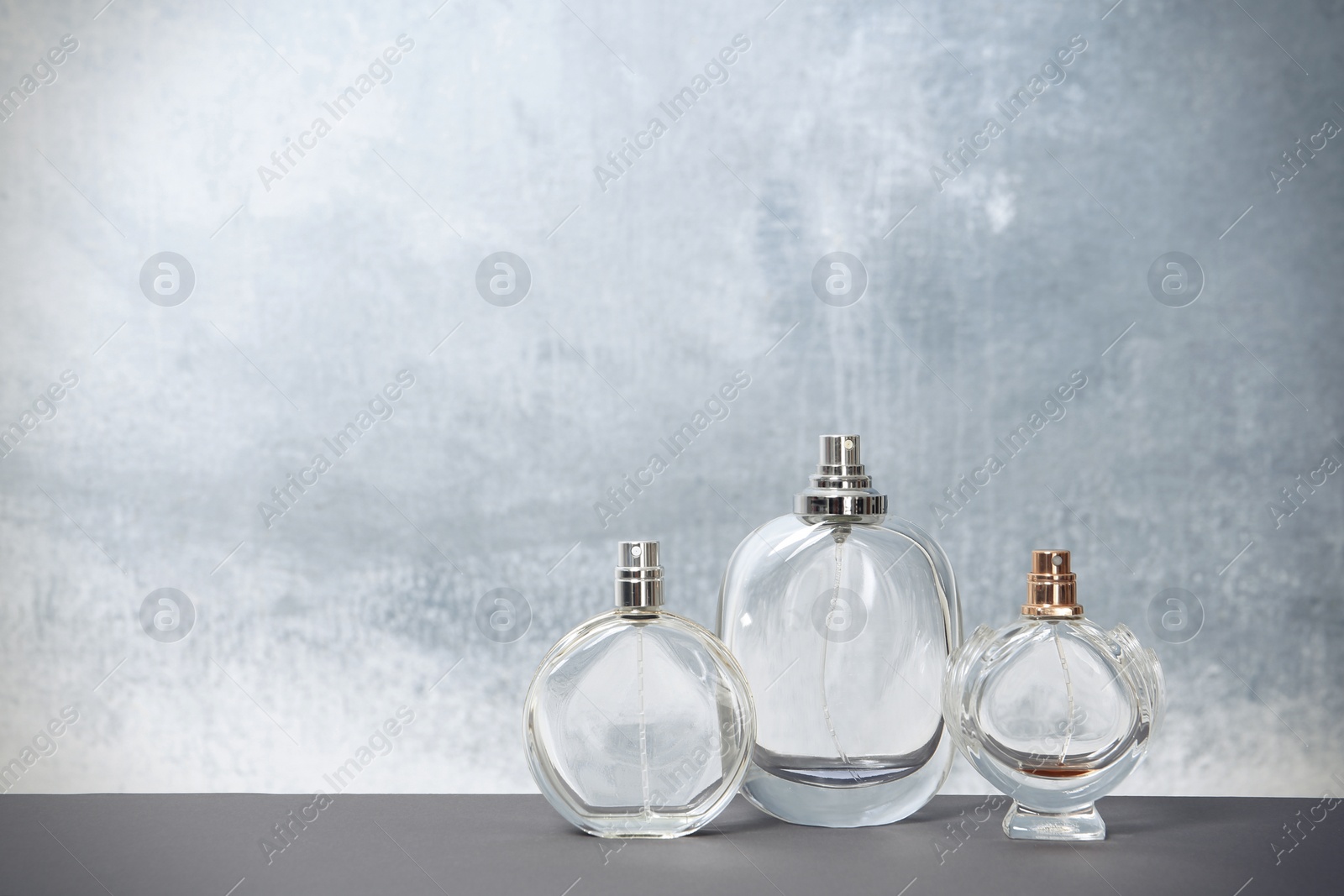 Photo of Different perfume bottles on table against color background