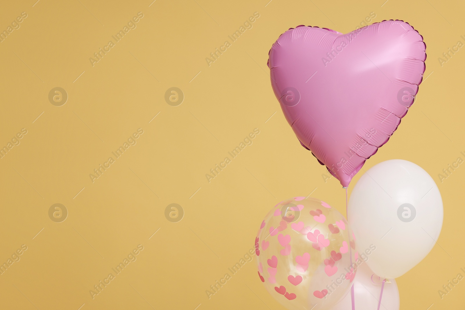 Photo of Bunch of heart and round shaped balloons on beige background, space for text. Birthday party