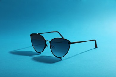 Photo of Sunglasses on light blue background. Stylish accessory