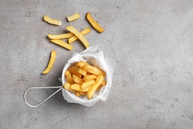Photo of Frying basket with tasty french fries on light grey table, flat lay. Space for text