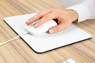 Woman using modern wired optical mouse at office table, closeup
