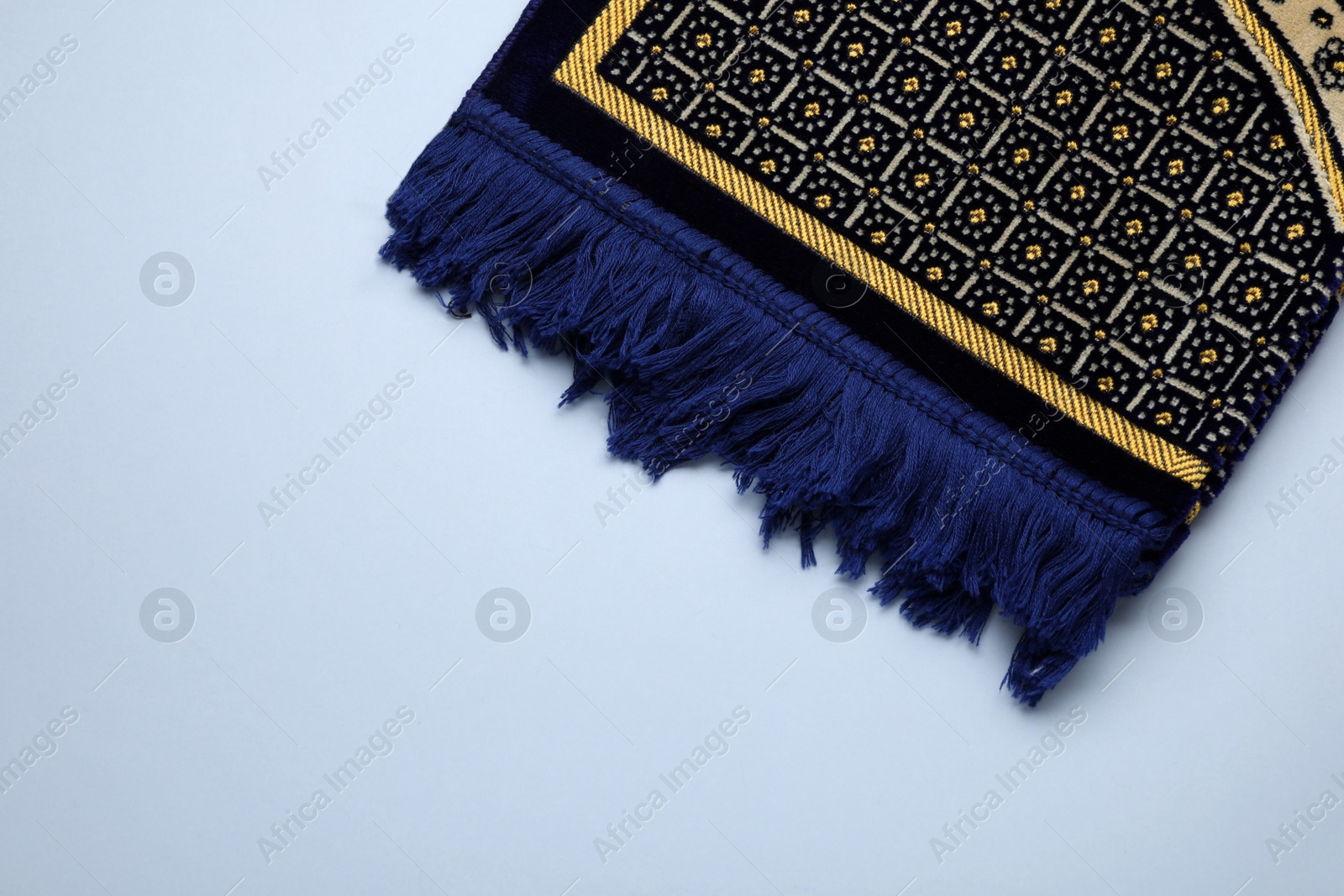 Photo of Muslim prayer rug on light background, top view. Space for text