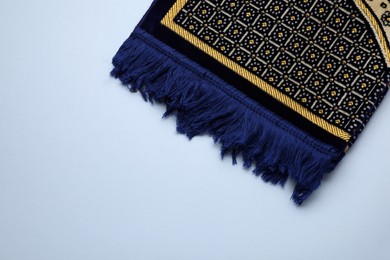 Photo of Muslim prayer rug on light background, top view. Space for text