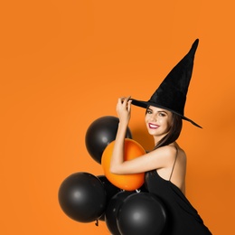 Beautiful woman wearing witch costume with balloons for Halloween party on yellow background, space for text