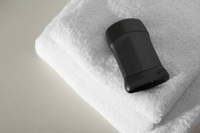 Deodorant with clean towels on light background, above view. Space for text