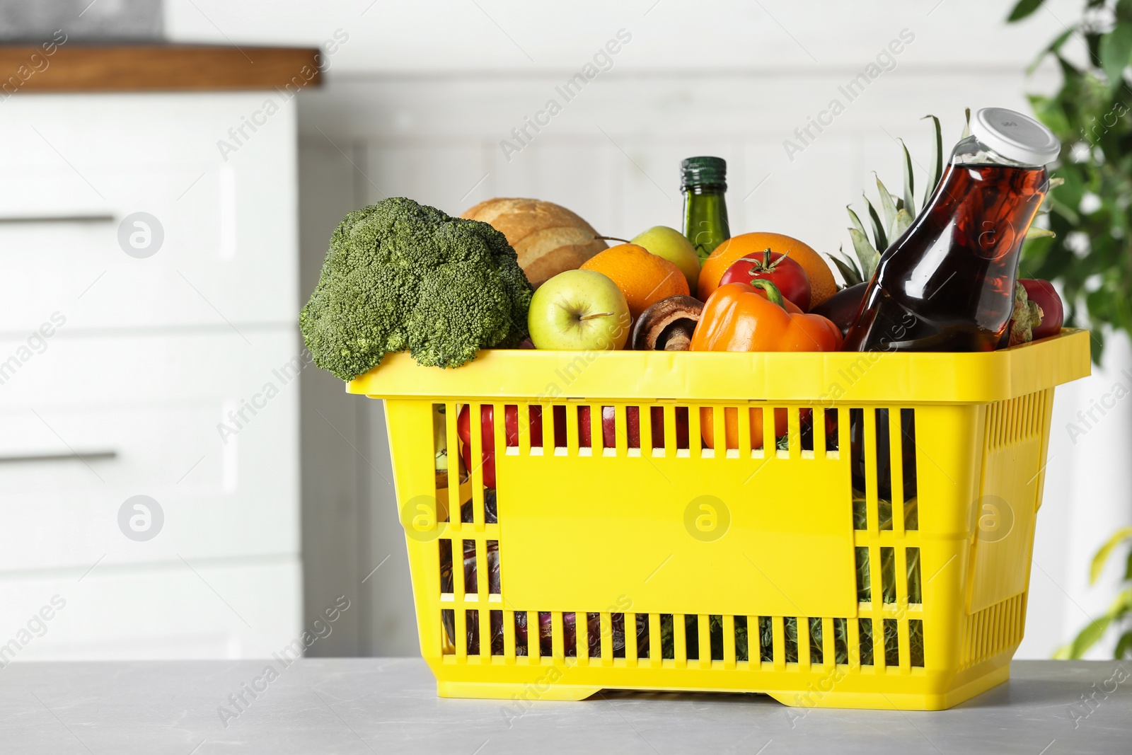 Photo of Shopping basket with grocery products on grey table indoors. Space for text