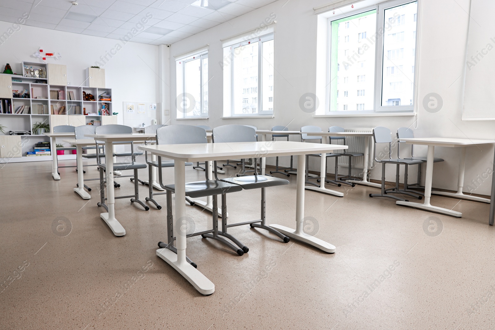 Photo of Empty school classroom with contemporary furniture and windows