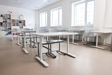 Empty school classroom with contemporary furniture and windows