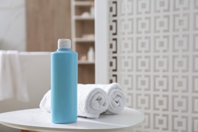 Photo of Bottle of shower gel and fresh towels on white table in bathroom. Space for text