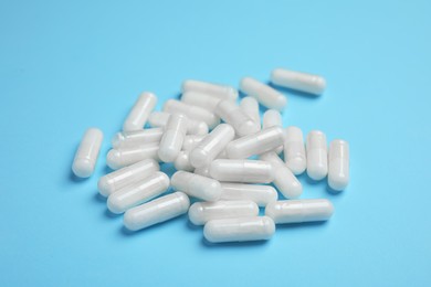 Photo of Pile of amino acid pills on light blue background, closeup