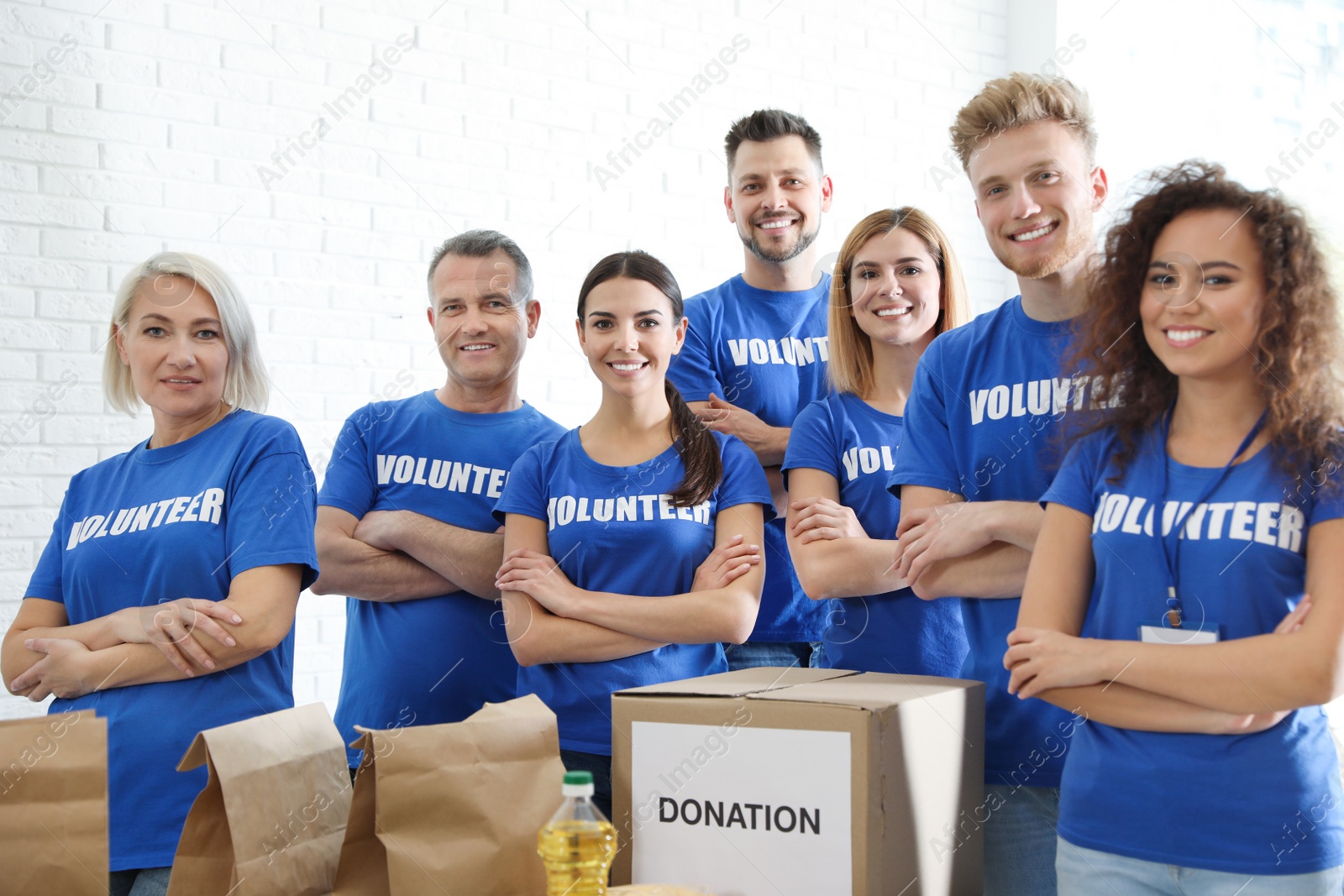 Photo of Team of volunteers near table with food donations indoors