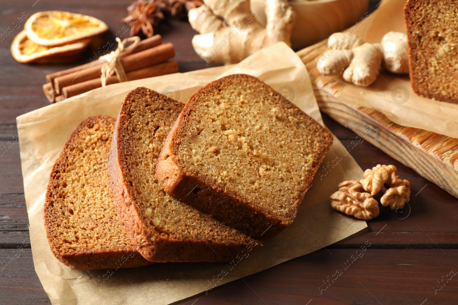 Photo of Delicious gingerbread cake and ingredients on wooden table, closeup