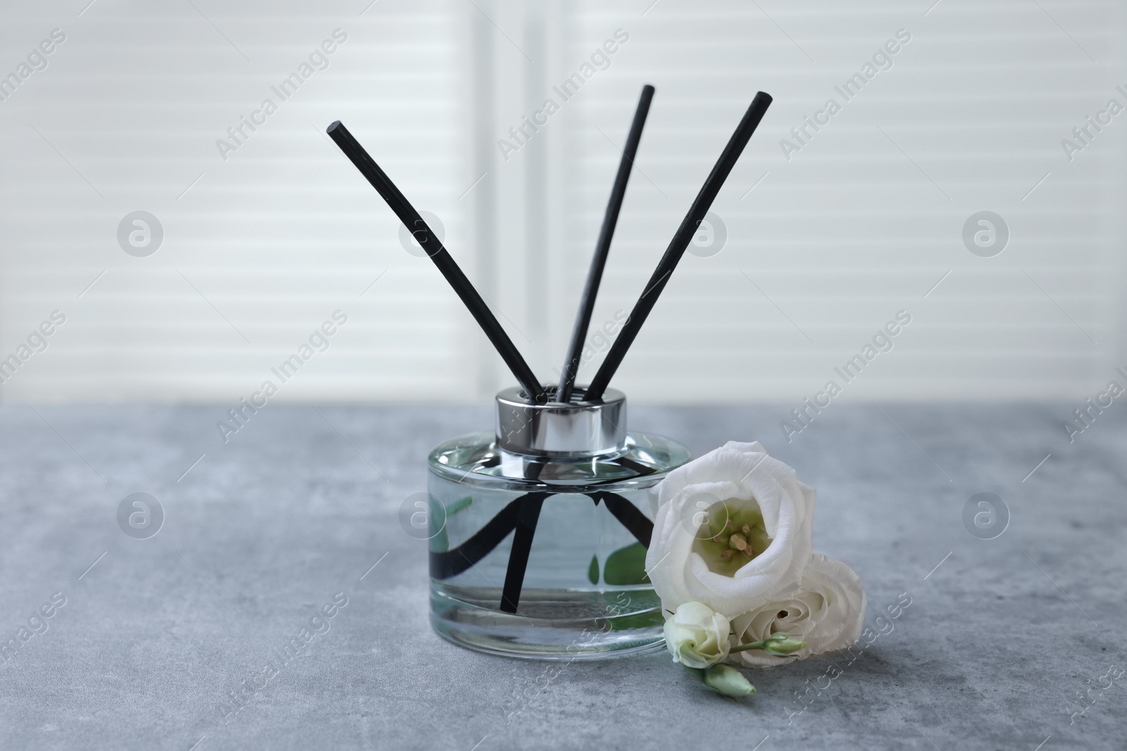 Photo of Reed diffuser and eustoma flowers on gray marble table