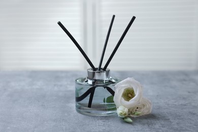 Photo of Reed diffuser and eustoma flowers on gray marble table