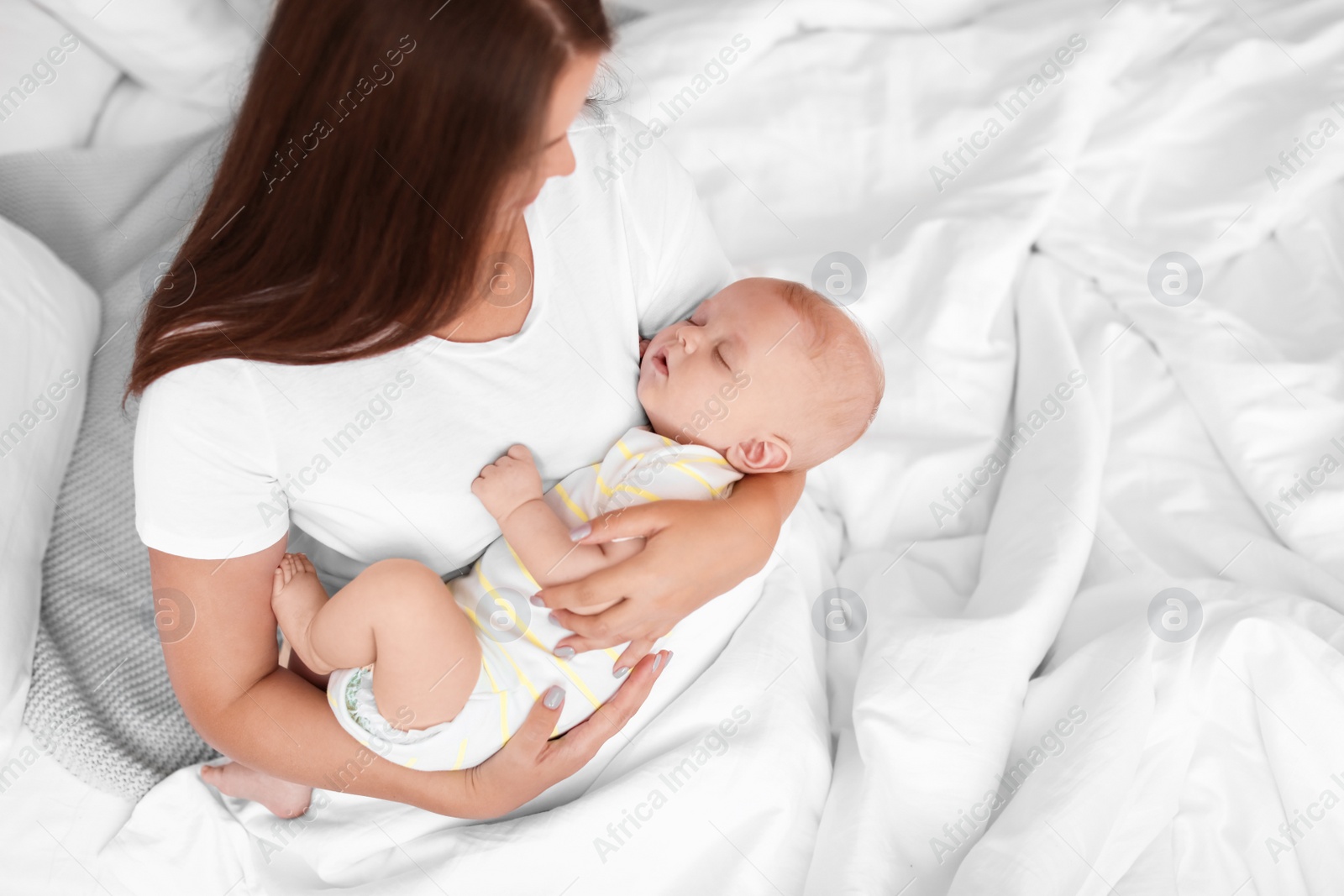 Photo of Mother with her sleeping baby in bed at home