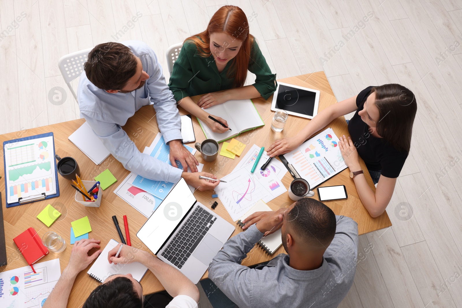 Photo of Team of employees working together at wooden table indoors, above view. Startup project