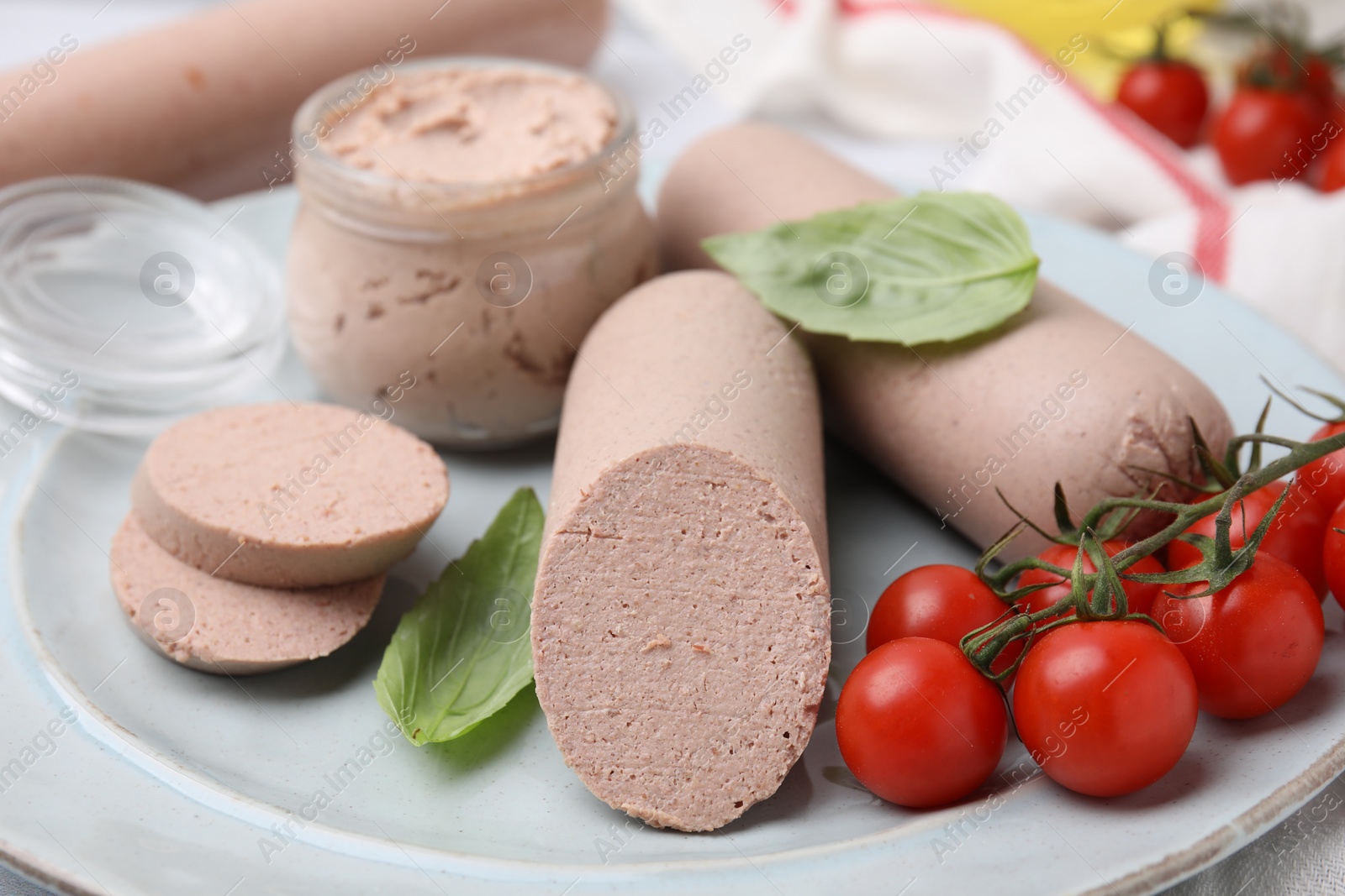 Photo of Delicious liver sausages, paste and cherry tomatoes on plate, closeup