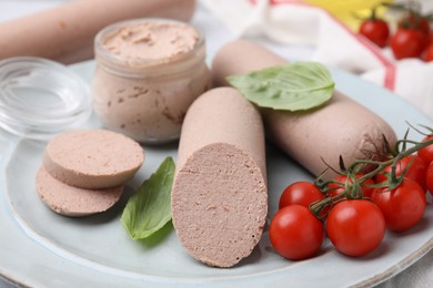 Photo of Delicious liver sausages, paste and cherry tomatoes on plate, closeup