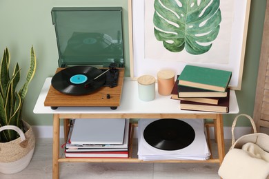 Photo of Stylish turntable with vinyl record on console table in cozy room