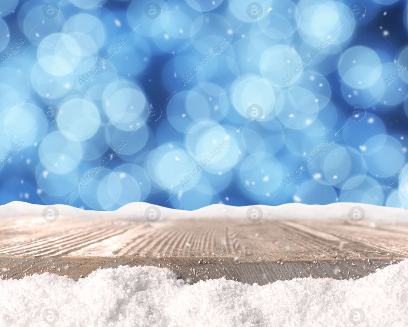 Image of Wooden surface with heap of snow and blurred Christmas lights on background, bokeh effect 