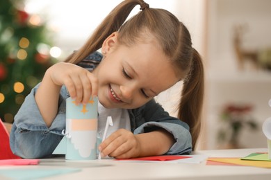 Photo of Cute little girl with paper Saint Nicholas toy at home