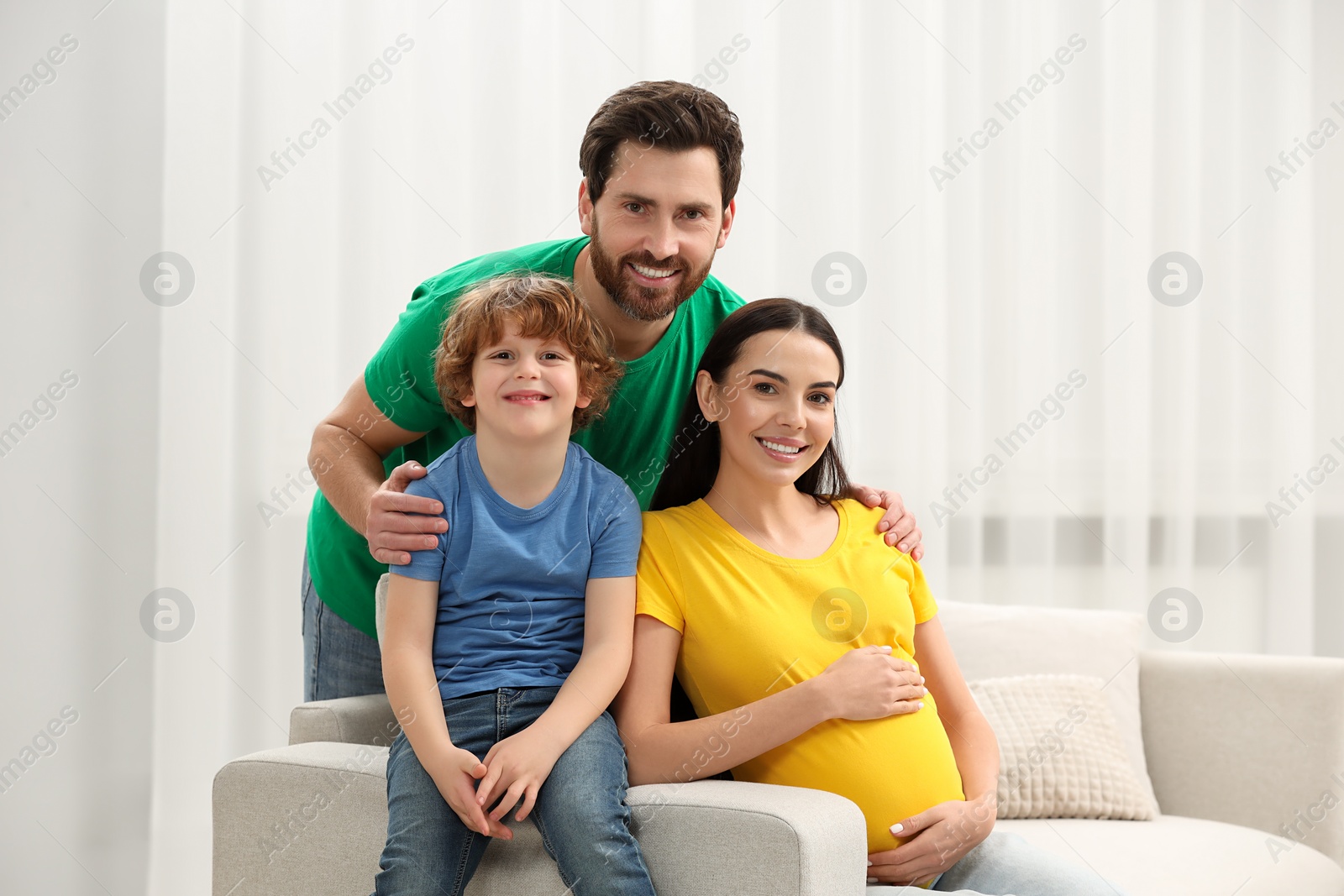 Photo of Family portrait of pregnant mother, father and son in house