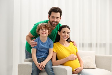 Family portrait of pregnant mother, father and son in house