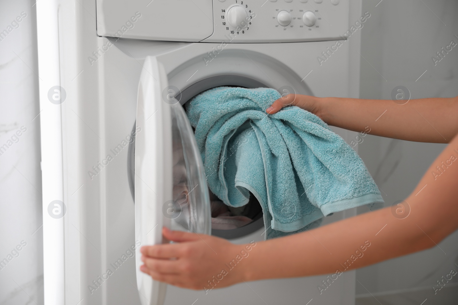 Photo of Woman putting dirty laundry into washing machine indoors, closeup