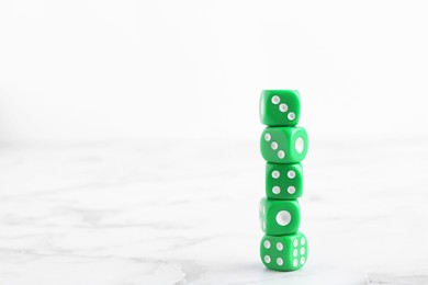Photo of Many stacked green dices on white marble table. Space for text