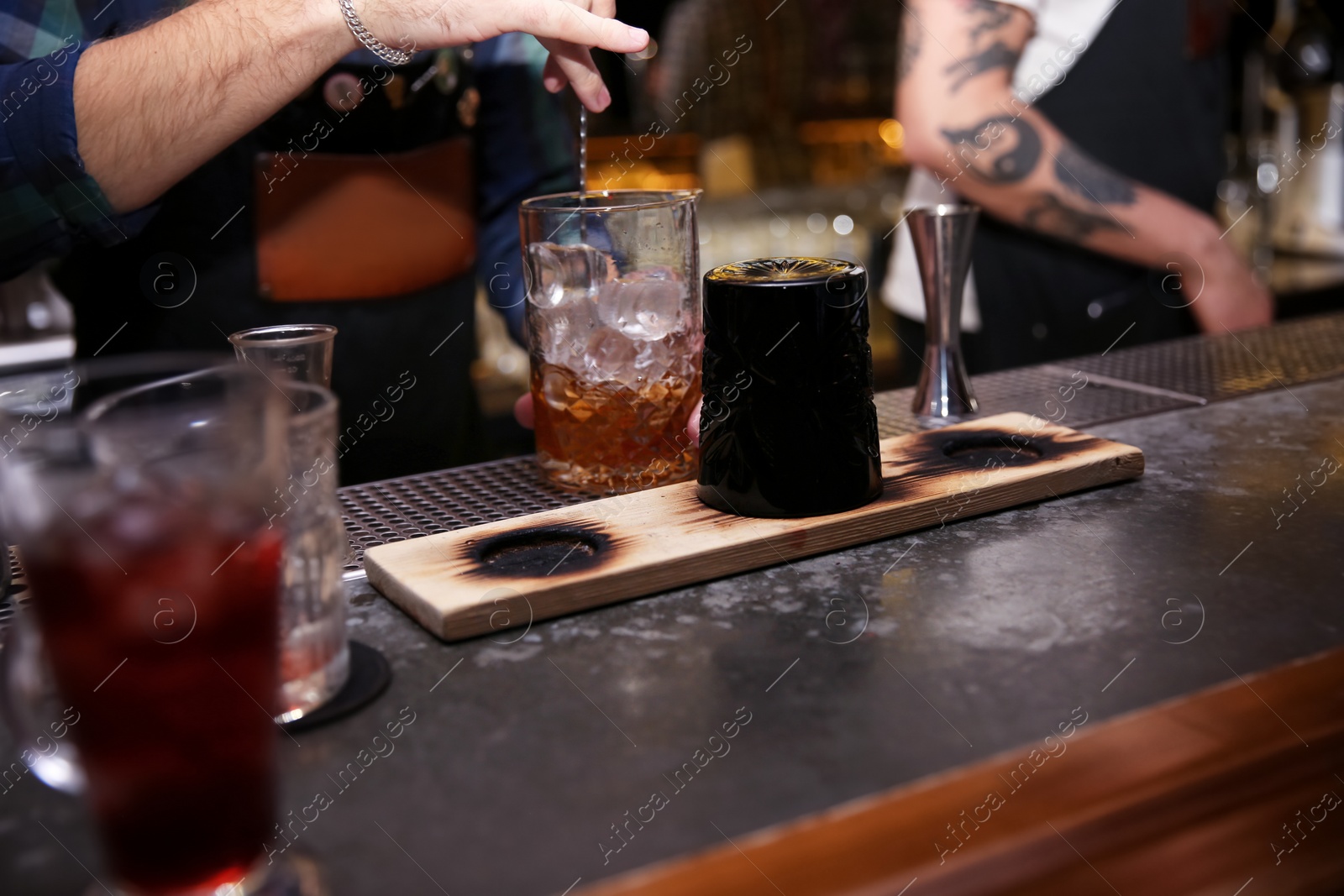 Photo of Bartender preparing tasty cocktail at counter in nightclub, closeup