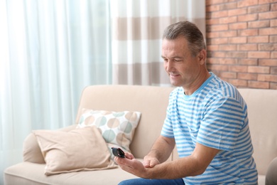 Photo of Mature man checking pulse with fingers in at home. Space for text