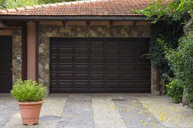 Photo of Beautiful house exterior with garage and green plants around driveway