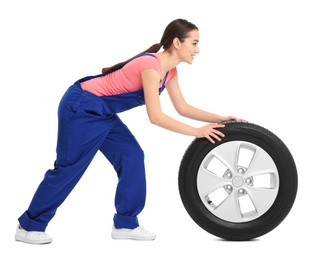 Female mechanic in uniform with car tire on white background