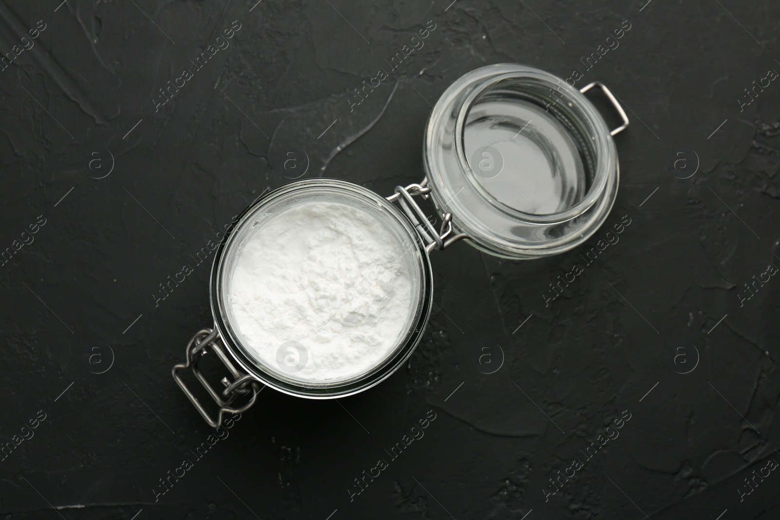 Photo of Baking powder in jar on black textured table, top view