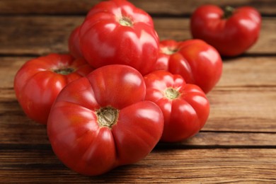 Photo of Whole ripe red tomatoes on wooden table, closeup