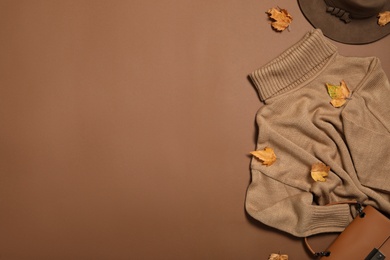 Photo of Flat lay composition with sweater and dry leaves on brown background, space for text. Autumn season