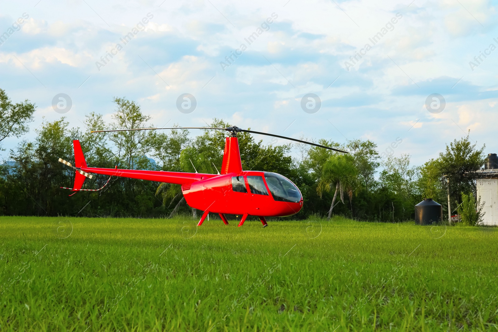 Photo of Modern red helicopter on green grass outdoors