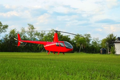 Modern red helicopter on green grass outdoors